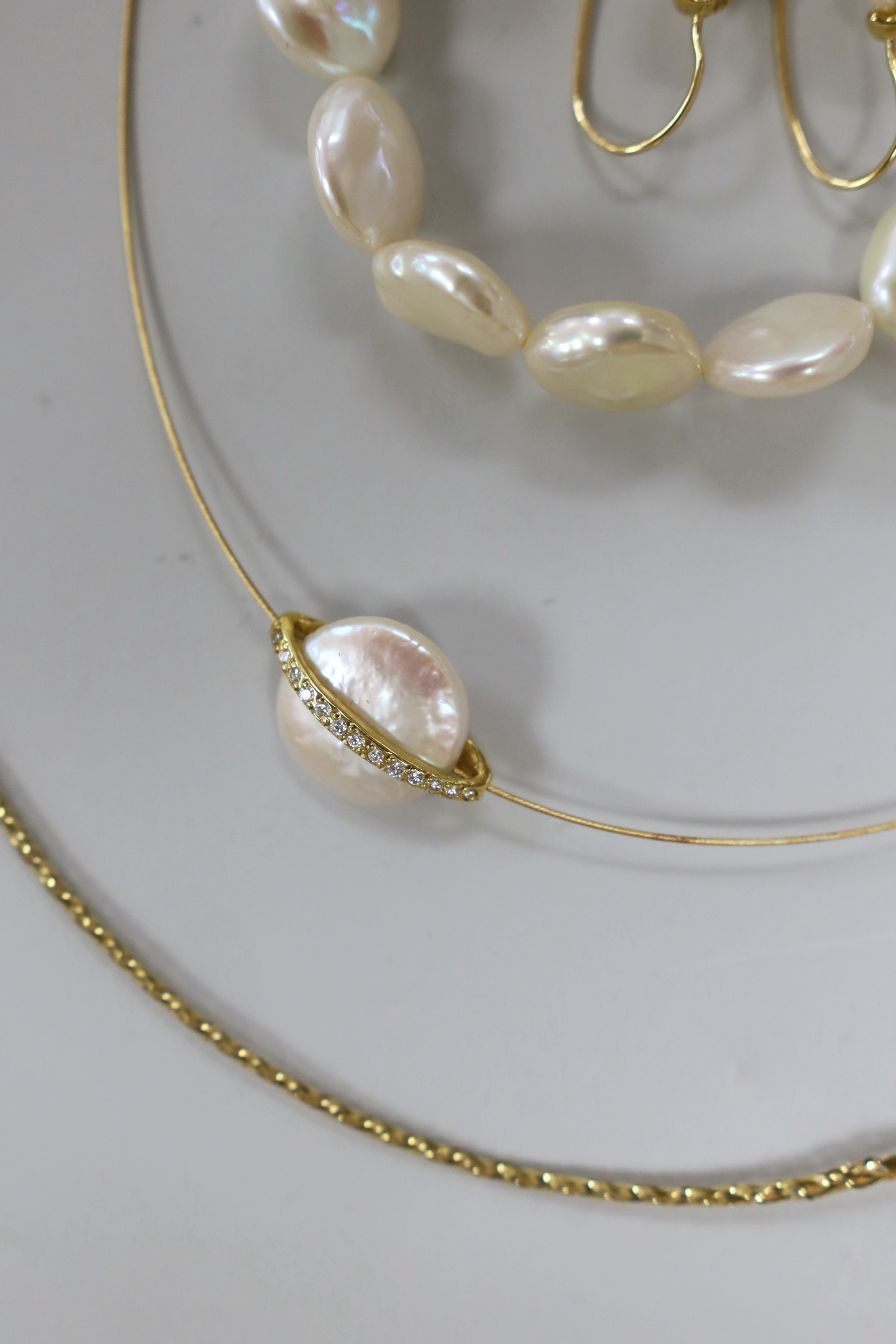 A modern suite of 750, diamond and button cultured pearl set jewellery, comprising a necklet and pair of earrings, together with a mother of pearl bracelet and a 375 necklet.